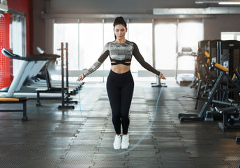 Wall Mural - Pretty young woman using jump rope in sports club