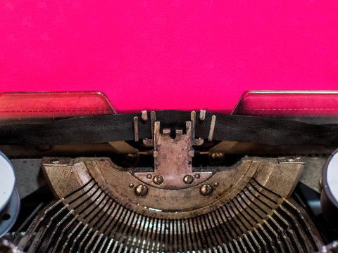 old vintage typewriter with a sheet of pink paper