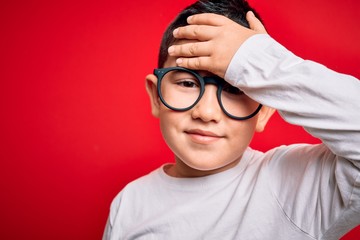 Sticker - Young little smart boy kid wearing nerd glasses over red isolated background stressed with hand on head, shocked with shame and surprise face, angry and frustrated. Fear and upset for mistake.