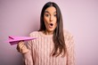© Krakenimages.com - Young beautiful brunette woman holding paper airplane over isolated pink background scared in shock with a surprise face, afraid and excited with fear expression