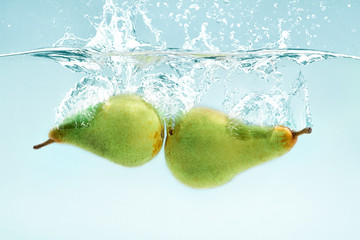 Aufkleber - Vitamin freshness. Green pears flying into transparent water on blue background