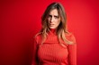 © Krakenimages.com - Young beautiful brunette woman wearing casual turtleneck sweater over red background skeptic and nervous, frowning upset because of problem. Negative person.