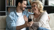 © fizkes - Overjoyed elderly mother and adult son relax using cellphone together