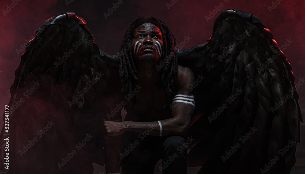 Foto fallen black Belial sitting on the ground and looking up isolated ...