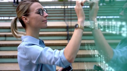 Poster - Young woman with cellular gadget in hand checking transport schedule on interactive information panel, intellectual female in spectacles tapping on sensory screen in public place