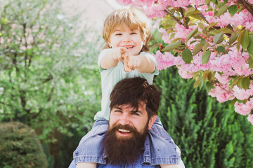 Wall Mural - Portrait of happy father giving son piggyback ride on his shoulders and looking up. Father With Son Having Fun In Park. Fathers day.