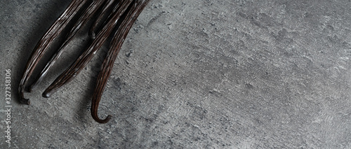 Fotomural Dark brown vanilla beans on gray stone like table, view from above, space for te