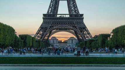 Wall Mural - Eiffel Tower day to night timelapse and people sitting on the grass in the evening in Paris, France