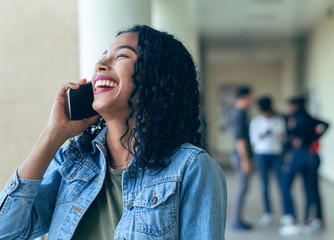 A college girl laughing with a call with her classmates in the background