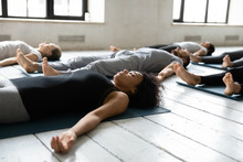Diverse People Resting After Yoga Workout Lying In Shavasana Pose