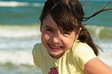  beautiful smiling girl posing on the seashore near a wooden pier.