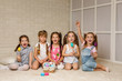 © producer - happy little child girls with basket with painted Easter eggs smiling while sitting on the floor of the room. friends celebrate Easter together