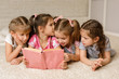 © producer - Group of kid lay down on floor and reading tale book. four little girls studying in the class together. friendship concept