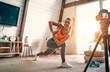 © Valerii Apetroaiei - Athletic woman blogger in sportswear shoots video on camera as she does exercises at home in the living room. Sport and recreation concept. Healthy lifestyle.