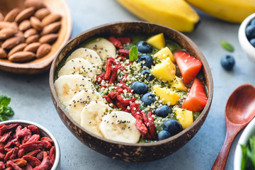 Superfood smoothie in coconut bowl with fruits and seeds toppings. Healthy eating, healthy lifestyle concept