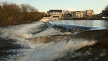 Slow Motion Of A Flooded UK River Creating A Heavy Waterfall Downstream.  The River Wharf In Otley Overflowing With High Water Levels During The UK Floods Shot In 50fps With Ability To Slow Down In Po