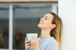 © PheelingsMedia - Happy woman relaxing in a terrace holding coffee mug