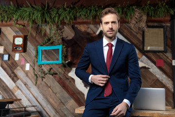 Wall Mural - confident businessman in suit adjusting coat in a coffeeshop