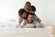 Happy young family with kids relax in bedroom