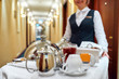 © Svitlana - All that you need. Waitress in uniform delivering tray with food in a room of hotel. Room service. Focus on tableware