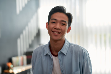 Happy at work. Portrait of a happy young asian man in casual wear looking at camera and smiling while working in the creative office. Young designer in the creative working space