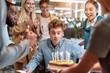 © Svitlana - Close your eyes and make a wish. Young happy man is going to blow candles on cake and make a wish while celebrating birthday with colleagues