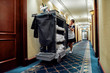 Cleaning at its finest. Full-length shot of hotel maid in uniform walking along the hall with chambermaid trolley. Room service concept.