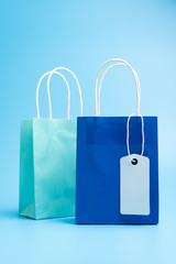 Wall Mural - Two blue shopping or gift bags with blank label tag isolated on blue background