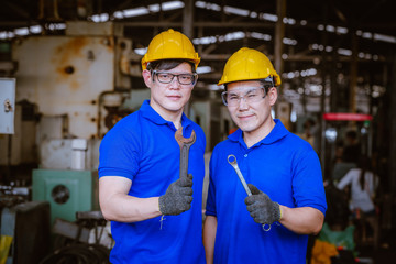 The Industry engineering wear causal  uniform hold wrench standing on control operating machine work in industry factory.