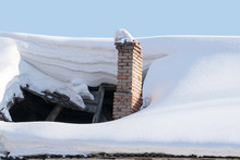 The Roof Collapsed Under The Weight Of Snow. Damaged Falling Roof And Chimney On Sunny Day With Clear Blue Sky. 
