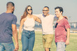© Mangostar - Happy four friends hugging while standing on meadow. Smiling young people embracing at nature. Union concept