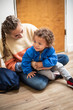 © Brocreative - Young bi-racial child being watched by a babysitter. Child care photo of a child care worker sitting with the young boy and smiling together
