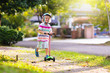 © famveldman - Little boy riding scooter. Kids ride kick board.