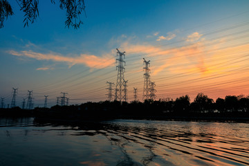 High voltage electrical tower and beautiful river nature landscape at sunset