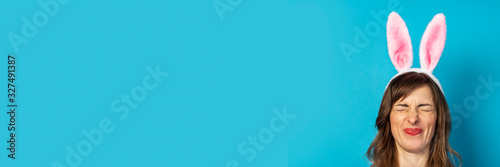 Fotomural Young woman with closed eyes and ears of a rabbit on a blue background