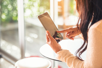 Asian woman using tablet shopping online website on smartphone with smiling face. Happiness asian woman holding cellphone checking mail from online shopping website read article Blog vlog social media