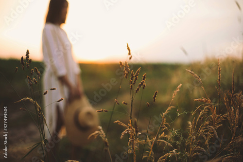 Fotografía Herbs and grasses in sunset light on background of blurred woman in summer meadow