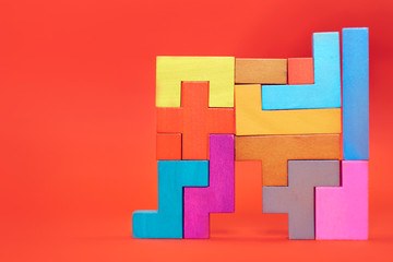 wooden block puzzle. wood cube stacking. Concept of complex and smart logical thinking. Slightly defocused and close up shot. on a red background