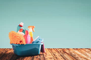 Detergents in a basin on a wooden table with copy space: spring cleaning concept