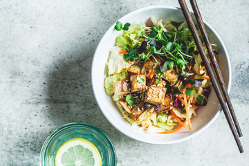 Canvas Print - Fried tofu salad with sprouts and sesame seeds in white bowl, top view. Vegan food, asian food concept.