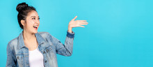 Banner Of Happy Asian Woman Feeling Happiness And Gesture Hand Open On Blue Background. Cute Asia Girl Smiling Wearing Casual Jeans Shirt And Present On Copy Space.