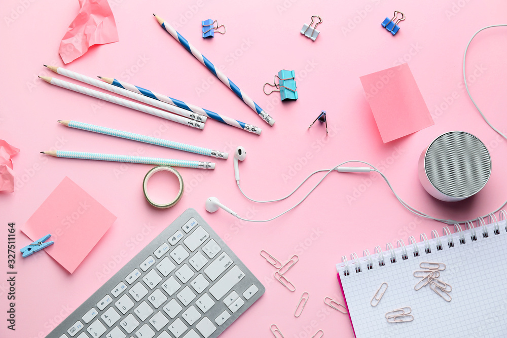 Computer keyboard with stationery on pink background