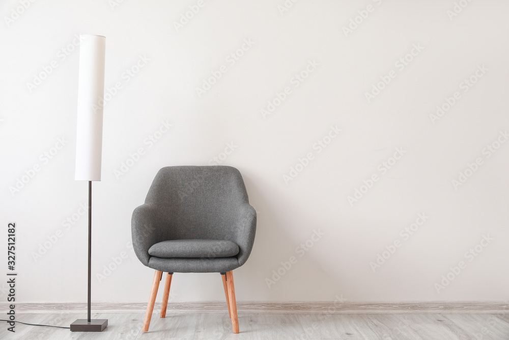 Armchair with lamp near white wall in room