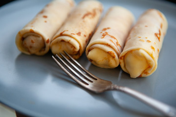 Wall Mural - twisted pancakes stuffed with straw on a dark plate