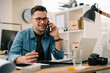 © JustLife - Businessman in office. Handsome man talking on phone at work.