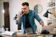 © JustLife - Businessman in office. Handsome man talking on phone at work.
