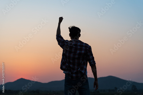 Cuadros en Lienzo Man with fist in the air during sunset sunrise mountain in background