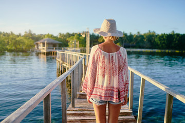 Poster - Vacation on tropical island.  Back view of young woman in hat enjoying sea view from wooden bridge terrace, Siargao Philippines