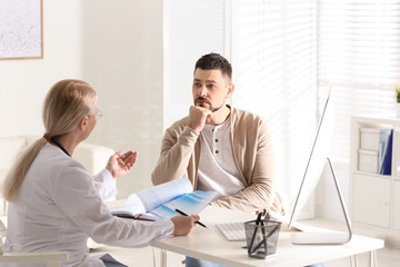 Wall Mural - Doctor consulting patient at desk in clinic