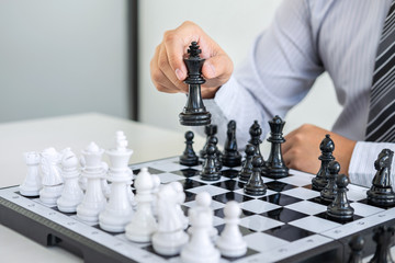 Black and White chess with player, Hands of businessman thinking to moving chess figure in competition and planning strategy to success play for win